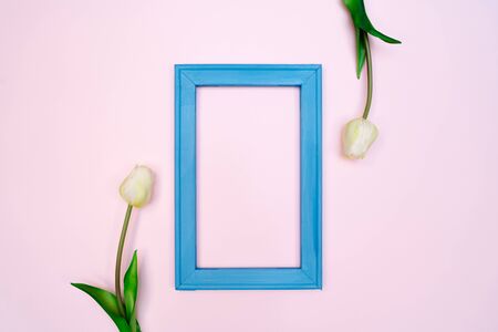 Flowers composition. tulip flowers with blue photo frame on pink background. Flat lay, top view, copy spaceの写真素材