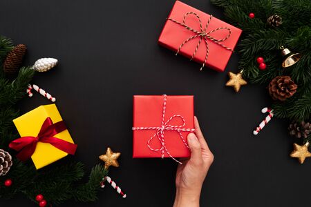 Hand hold christmas gift box with pine tree and xmas decoration on black backgroundの写真素材