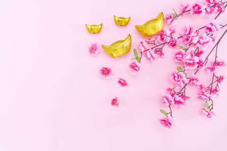 Flat lay Chinese lunar new year gold money and flower on pink backgroundの写真素材