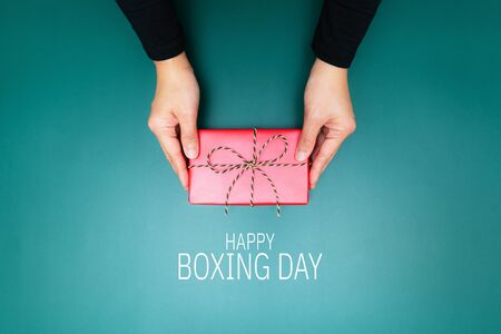 Happy Boxing Day, young woman hand with a gift box offer to receiverの写真素材