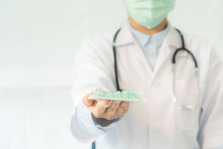 Coronavirus stop infection. Give a mask, young female doctor or intern wearing protective mask and stethoscope against infectious diseases and flu. Healthcare, medical education, emergency medical service, surgery  conceptの写真素材