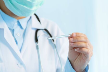 Coronavirus stop infection. young female doctor wearing mask with thermometer and stethoscope against infectious diseases and flu. Healthcare, medical education, emergency medical service, surgery conceptの写真素材