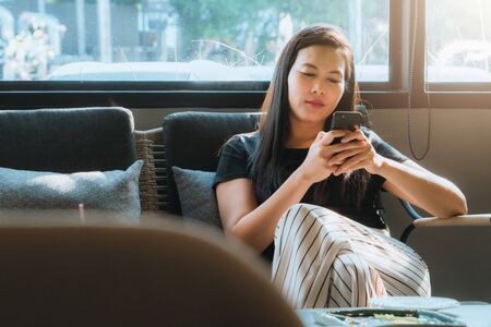 young asia woman reading message in smartphone at coffee shopの写真素材