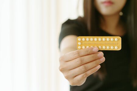 Woman holding contraception pills at home, closeup. Gynecology conceptの写真素材