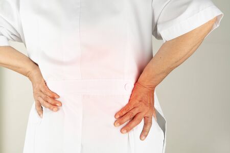 senior doctor woman suffering of backache, touching back with hand, muscular pain over white backgroundの写真素材