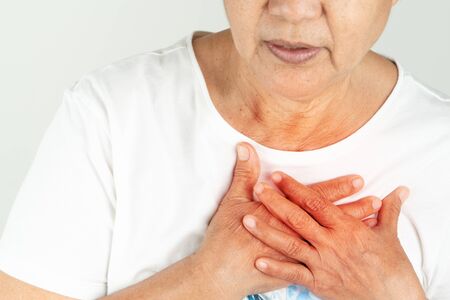 Old woman heart attack holding breast on white backgroundの写真素材