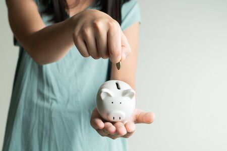 Saving and business concept, Cute girl with piggy bank and coins at homeの写真素材