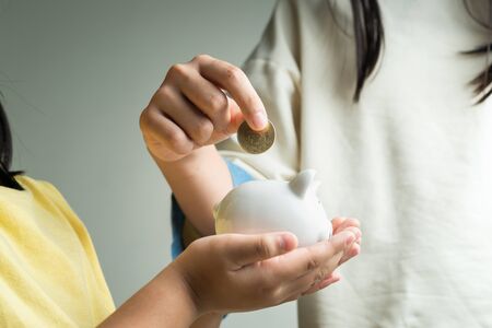 Saving and business concept, two little girl with piggy bank and coins at homeの写真素材