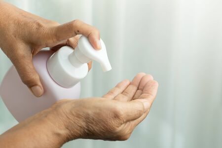 Covid-19 Coronavirus hand cleansing concept, senior hand apply alcohol gel or anti bacteria soap to make cleaning and clear virus, germ, bacteriaの写真素材