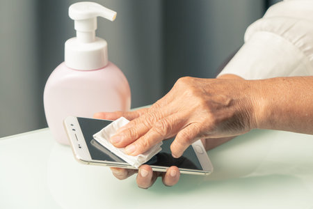 Covid-19 Coronavirus hand cleansing smartphone concept, senior hand wipe smartphone with alcohol gel...