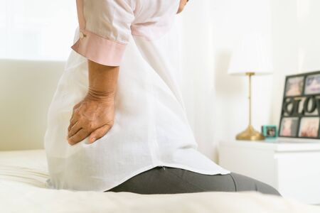 Back pain of old woman at home, healthcare problem of senior conceptの写真素材