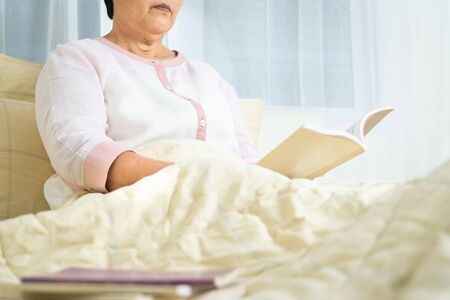 quarantine activity for senior woman read a book stay home to avoid riskの写真素材