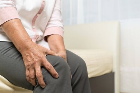Knee pain of old woman at home, healthcare problem of senior conceptの写真素材