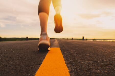 Athlete running on the road trail in sunset training for marathon and fitness. motion blur of woman exercising outdoorsの写真素材