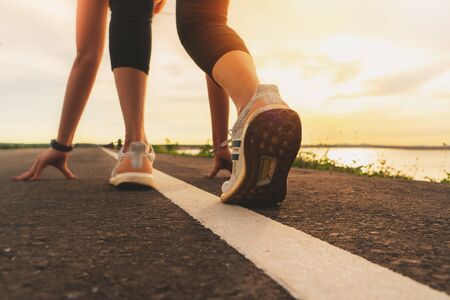 sport runner feet running on sunset lake closeup on shoeの写真素材