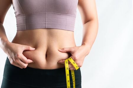 fat woman, fat belly, chubby, obese woman hand holding excessive belly fat with measure tape, woman diet lifestyle conceptの写真素材