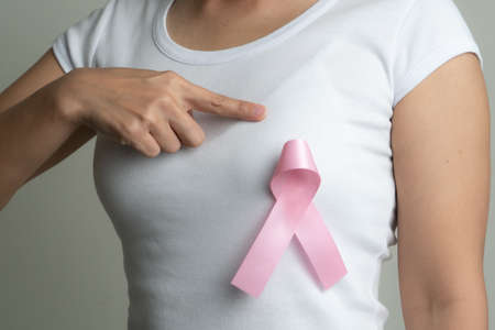pink badge ribbon on woman chest to support breast cancer cause. breast cancer awareness conceptの写真素材