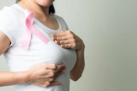 pink badge ribbon on woman chest to support breast cancer cause. breast cancer awareness conceptの写真素材