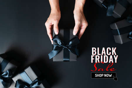 black friday sale, woman hand give the gift box on black backgroundの写真素材