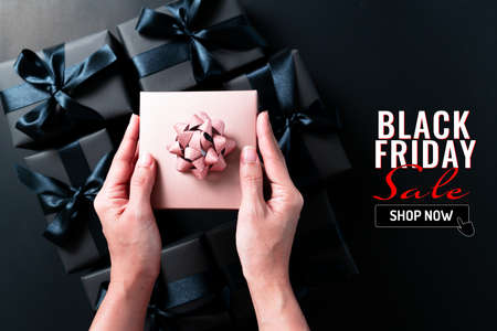black friday sale, woman hand give the gift box on black backgroundの写真素材