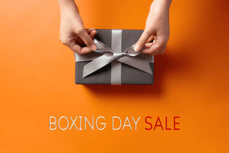 Boxing Day sale, young woman hand with a gift box offer to receiverの写真素材