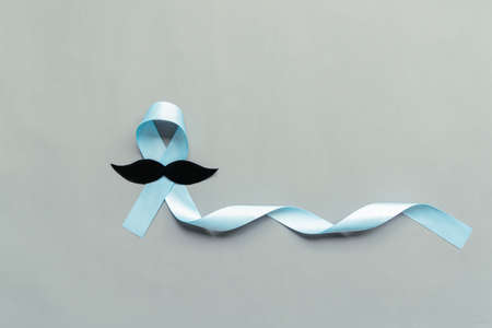 November light blue ribbon with mustache on gray background with copy space, Prostate cancer awareness month, men's health conceptの写真素材