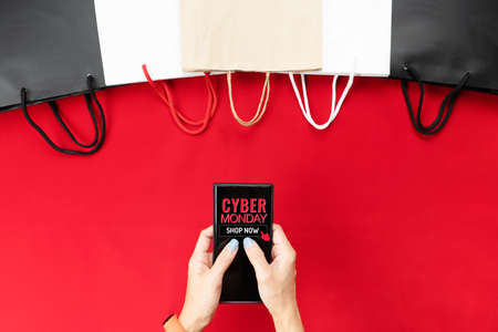 Cyber Monday Sale Clearance Discount Concept, woman hand holding smartphone with shopping bag.の写真素材