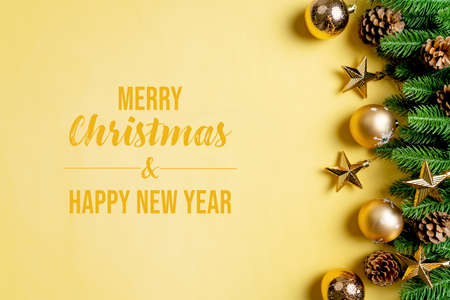 Christmas ball and pine tree with xmas decoration on yellow backgroundの写真素材