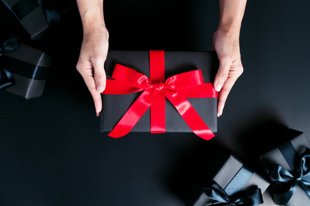 Boxing day Sale concept, woman hand give the gift box on black backgroundの写真素材