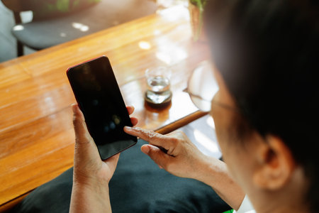 senior lady sitting in a chair and touching the screen of smartphone, online shopping conceptの写真素材