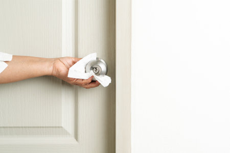 Cleaning door knob with alcohol spray for Covid-19 Coronavirus preventionの写真素材