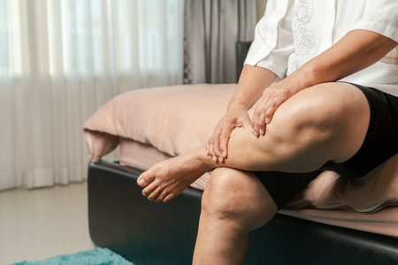 leg cramp, senior woman suffering from leg cramp pain at home, health problem conceptの写真素材
