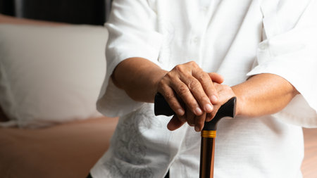 Senior back pain woman with walking stick at homeの写真素材