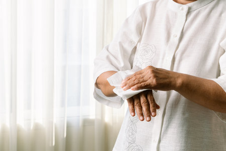 Senior woman cleaning her hands with white soft tissue paper. isolated on a white backgroundsの写真素材