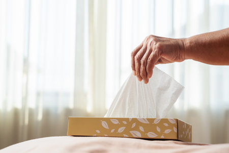 Senior women hand picking napkin/tissue paper from the tissue boxの写真素材