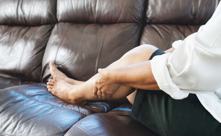 leg cramp, senior woman suffering from leg cramp pain at home, health problem conceptの写真素材