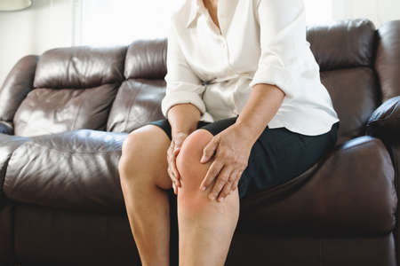 senior woman suffering from knee pain at home, health problem conceptの写真素材