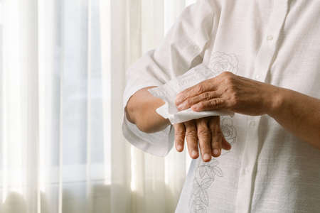 Senior woman cleaning her hands with white soft tissue paper. isolated on a white backgroundsの写真素材