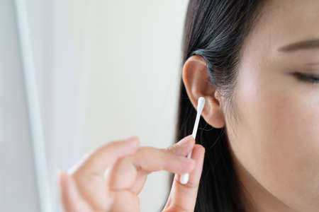 woman cleaning ear with cotton swab. Healthcare and ear cleaning conceptの写真素材