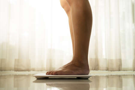 young woman standing on digital weight scaleの写真素材