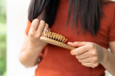 long loss hair on woman brush with and woman looking at her hairの写真素材