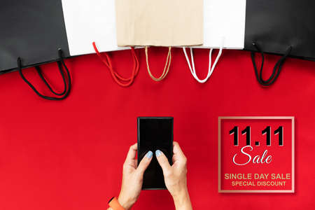 China 11.11 single day sale concept, woman hand holding smartphone with shopping bag.の写真素材