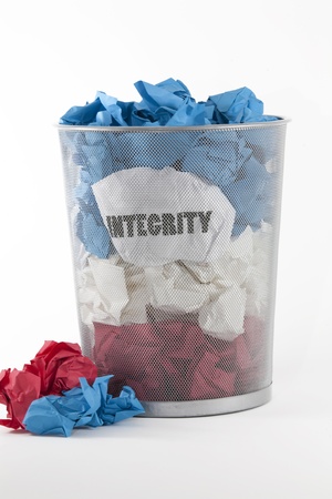 Politics and Integrity.A waste basket with red, white and blue wads of paper against a white background. The word INTEGRITY is written on one wad of white paper.の写真素材