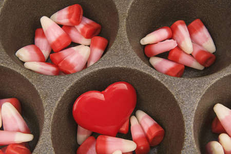 Red, white and pink candy corn in cast iron muffin pay with large red heart の写真素材