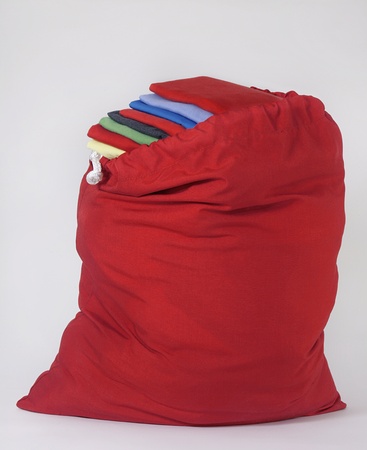 Red Laundry Bag with Bright Folded Shirts Piled on Each Otherの写真素材