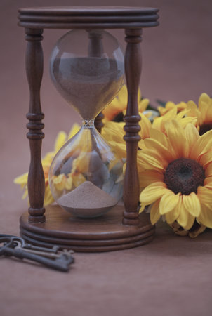 Hourglass, black-eyed susan, and skeleton keys on beige background  Selective focus 