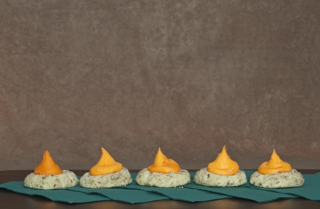 Five Cookies with in a Row with orange icing sitting on green napkins against a brown stucco backgroundの写真素材