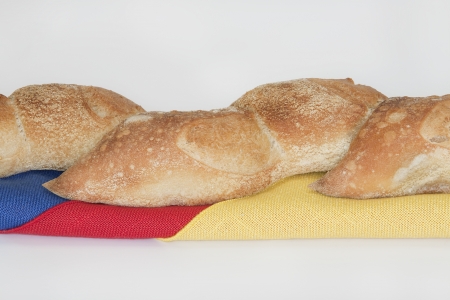 Closeup of Artisan bread loaf placed on blue, red, yellow linen napkins against white backgroundの写真素材