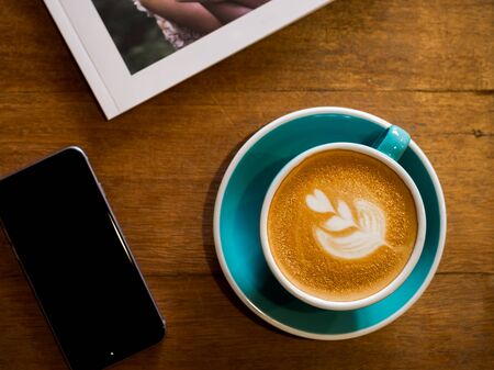 Overhead shot a book, cell phone and cup of coffee over a wooden backgroundの写真素材