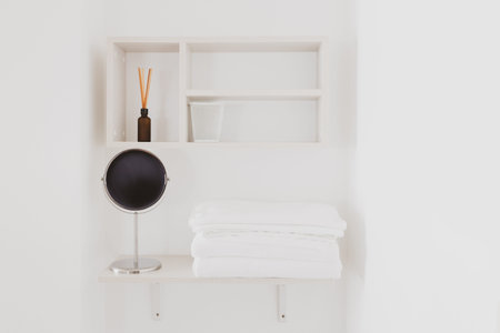 Clean and hygiene stack of white folded towel on white shelf with other hotel amenities; incense,...